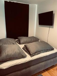 a bed with two pillows and a tv on the wall at BySeyn - 60qm mitten in der Erfurter Altstadt in Erfurt