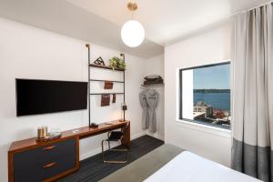 um quarto com uma secretária, uma televisão e uma janela em The State Hotel em Seattle