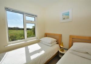 a bedroom with two beds and a large window at Sandhills 9 in Padstow