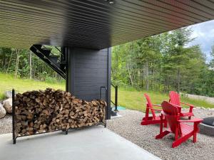 a pile of fire wood next to two red chairs at Au Coin Du Belvédère in Saint Come