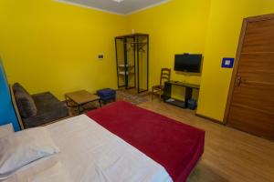 sypialnia z łóżkiem i telewizorem oraz żółtymi ścianami w obiekcie Koisha w mieście Biszkek