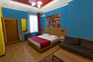 a bedroom with blue walls and a bed and a couch at Koisha in Bishkek