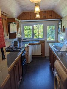 a kitchen with wooden cabinets and a stove top oven at 2 Bed Cottage Dog Child Friendly 15min walk to beach in Ederyn