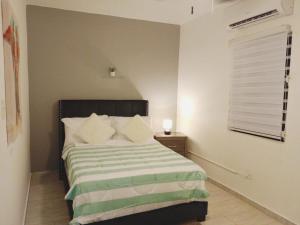 a bedroom with a bed with a green and white blanket at Urban Lodgings Two @ Roosevelt 457 in San Juan