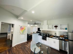 cocina con armarios blancos y mesa de cristal en Sonsak - Unit 2 en Charlottesville