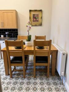 a wooden table with two chairs and a vase with flowers on it at Luxury Victorian spacious flat in Glasgow