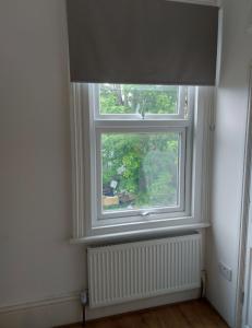 a window with a shade and a radiator in a room at W13 x Weekly Monthly Discount in London
