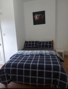 Una cama en un dormitorio con una manta de cuadros azul en W13 x Weekly Monthly Discount, en Londres