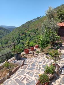 a stone patio with potted plants on a hill at Ceira Cottage - Refúgio de Charme Serrano in Góis