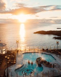 two people in a swimming pool overlooking the ocean at sunset at Oak Bay Beach Hotel in Victoria