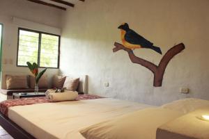 Ayenda Eufonia Hotel Natural في هوندا: غرفة نوم بسريرين وطائر على الحائط