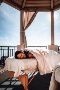a woman laying on a bed on a balcony at Oak Bay Beach Hotel in Victoria