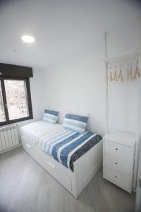 a white bedroom with a bed and a window at La estrella VUT4497AS in Gijón