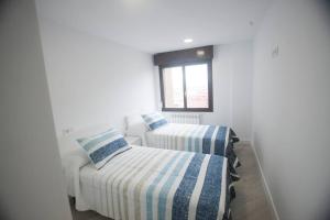 two twin beds in a room with a window at La estrella VUT4497AS in Gijón