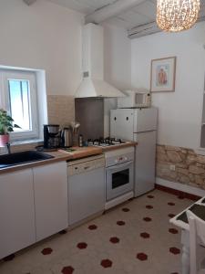 La cuisine est équipée de placards blancs et d'un four avec plaques de cuisson. dans l'établissement Le Petit Mas des Alpilles en Provence, à Saint-Étienne-du-Grès