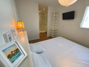 a bedroom with a white bed and a television at Charmant studio Pornicais in Pornic