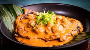 a black bowl of food with mushrooms and sauce at Summer C in Macanal
