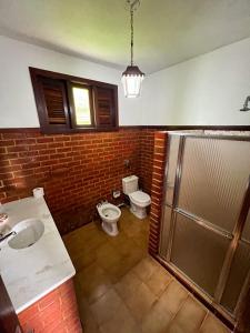 uma casa de banho com um WC, um lavatório e um chuveiro em Chale das hortensias em Petrópolis