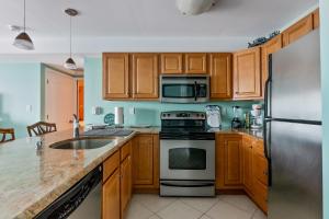a kitchen with wooden cabinets and stainless steel appliances at Nw Resort Condo W Stunning Ocean Views in North Wildwood