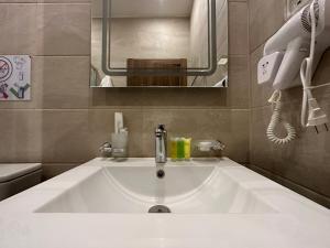 een witte wastafel in een badkamer met een spiegel bij Jasmine flower hostel in Madaba