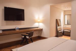 una camera d'albergo con scrivania e TV a parete di Hotel Marielena a Cuatrociénegas de Carranza