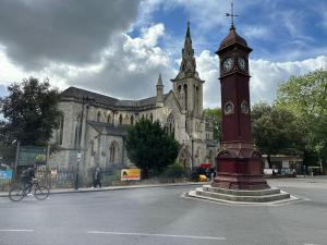 uma torre de relógio em frente a uma velha igreja em Stunning Flat in Highbury Hill em Londres