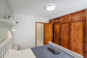 a bedroom with wooden cabinets and a bed with a blue blanket at One-bedroom with views of Los Gigantes in Santiago del Teide