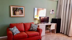 un soggiorno con divano rosso e una scrivania con computer di Hotel Libertà a Palermo