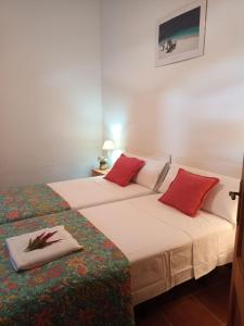 2 bedden in een kleine kamer met rode kussens bij Casa Alameda in Benarrabá
