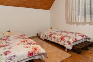 2 Betten in einem Zimmer mit weißen Wänden und Holzböden in der Unterkunft Baba's House in Raška