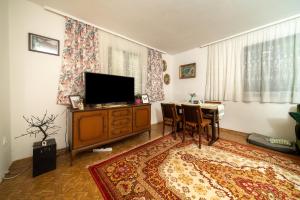 salon z telewizorem i stołem z krzesłami w obiekcie Baba's House w mieście Raška