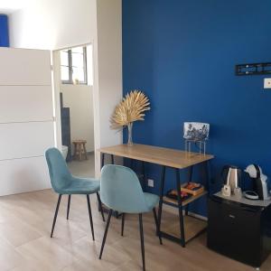 een tafel en 2 stoelen in een kamer met een blauwe muur bij LE CLOS DES LYS - Chambres avec jacuzzi - Nemours in Treuzy-Levelay