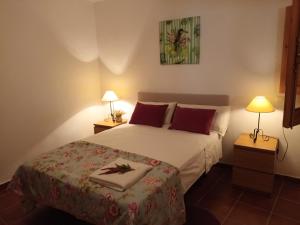 1 dormitorio con 1 cama con almohadas rojas y 2 lámparas en Casa Alameda en Benarrabá