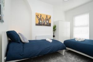 una camera con due letti con lenzuola blu di Dacy Lodge - Anfield Apartments a Liverpool
