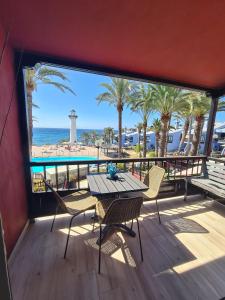 einen Tisch und Stühle auf einem Balkon mit Blick auf den Strand in der Unterkunft INFINITY VIEW in Playa del Aguila