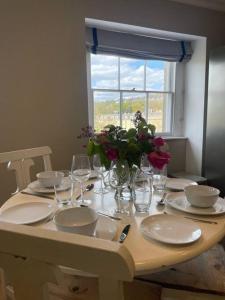 a table with plates and glasses and a vase of flowers at Crescent Penthouse with Stunning Views and free parking in Bath