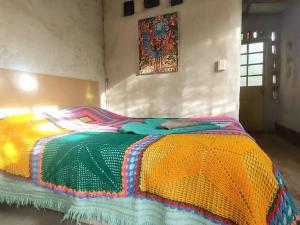 Una cama con una manta de colores en una habitación en ECO-LOFT, Sombra de Chañar,- Mallín Córdoba in 