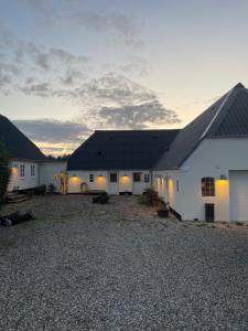 a group of white buildings with a gravel yard at Ferielejlighed på Elmensbjerg in Asperup