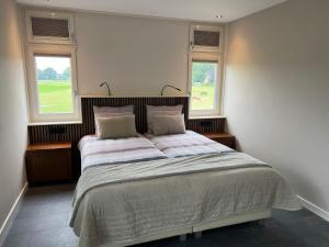 1 dormitorio con 1 cama grande y 2 ventanas en Peerd van ome Luuks (appartement met één of twee slaapkamers) en Kloosterhaar