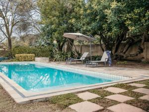 una piscina con 2 sillas y una sombrilla en SchoemansRus, en Riebeek-Wes