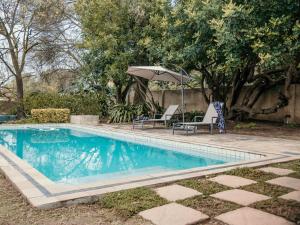 a swimming pool with two chairs and an umbrella at SchoemansRus in Riebeek-Wes
