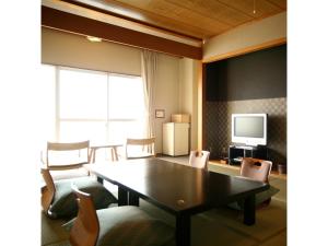 ein Esszimmer mit einem Tisch, Stühlen und einem TV in der Unterkunft Seaside Hotel Geibousou - Vacation STAY 92572v in Shima