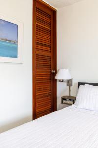 1 dormitorio con cama blanca y puerta de madera en Avila Suites, en San Juan