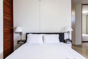 1 dormitorio con 1 cama blanca grande y 2 lámparas en Avila Suites, en San Juan