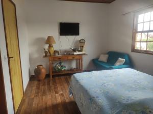 una camera con letto, TV e sedia di Apartamento Bela Vista a Tiradentes