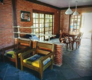 CASA CAMPESTRE COM PISCINA في كابيديلو: غرفة مع طاولة وكراسي وجدار من الطوب