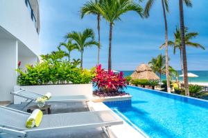 a swimming pool with palm trees and the ocean at Hyatt Ziva Puerto Vallarta in Puerto Vallarta