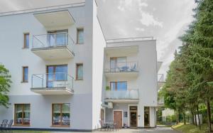 a white apartment building with balconies and trees at Apartament Dominikana 13 in Sianozety