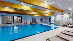 a large indoor pool with blue water in a building at Apartament Dominikana 13 in Sianozety +7 photos