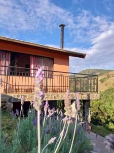 une maison avec un balcon et des fleurs devant elle dans l'établissement Chalé Canto Mundo, à Brazópolis